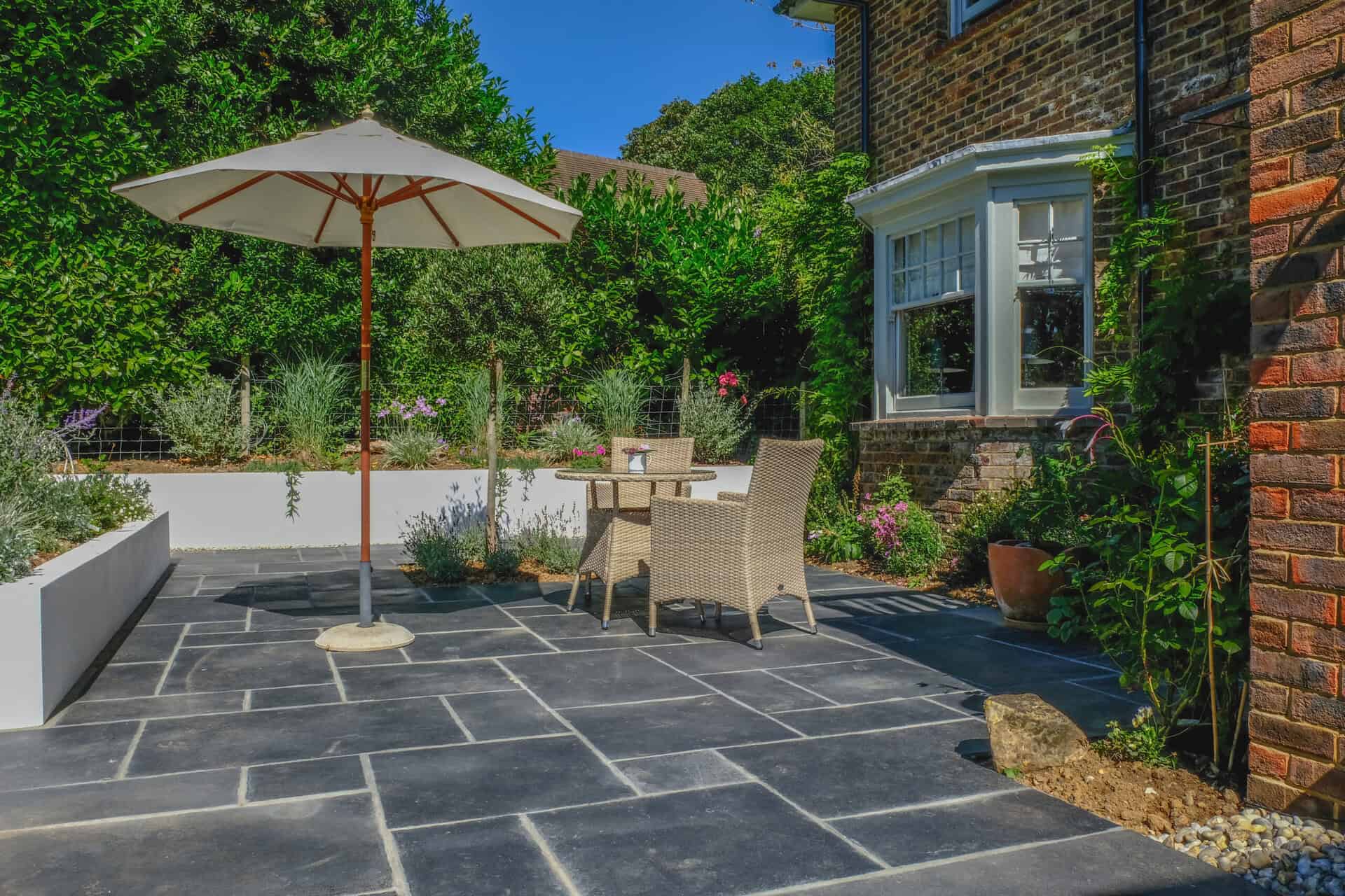 Table and chairs on the patio in an English country garden. Taken on a sunny summer day with plants and flowers.